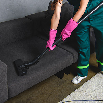 Made Perfect Cleaning Services crew in uniform cleaning a sofa with a vaccum